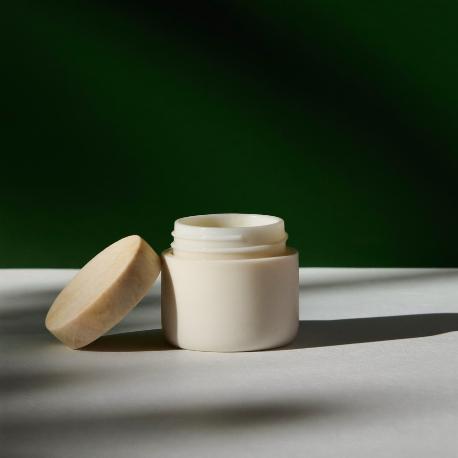 Piccolo vasetto tondo in ceramica bianca del Balsamo Labbra con coperchio in pietra appoggiato accanto